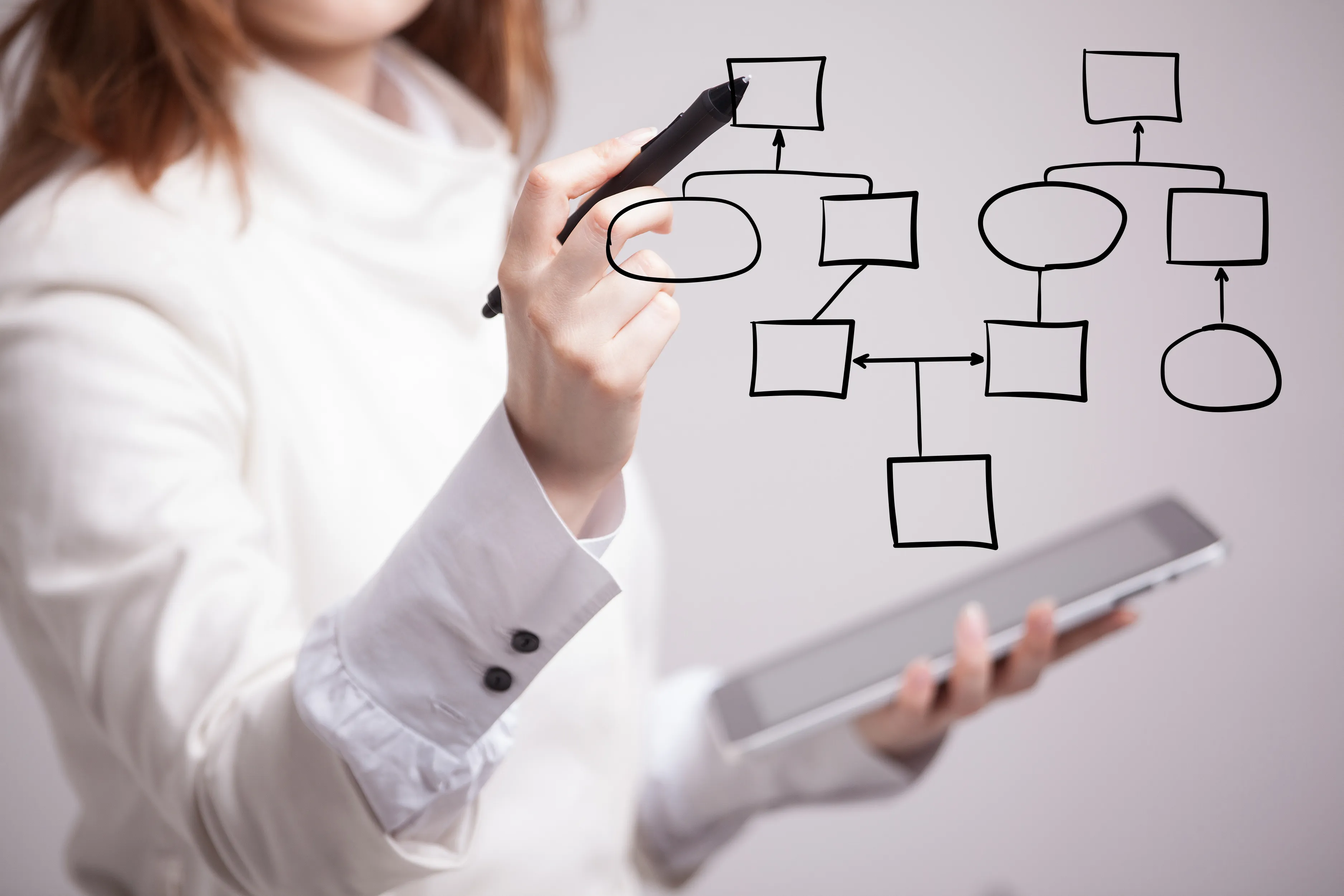 A consultant sketching a process flowchart while holding a tablet.
